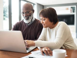 Cropped shot of a happy couple using a laptop in their living room to look at their finances